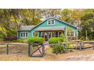 Charming green home with lush landscaping, mature trees and inviting front porch at 755 Jumbo Ln, Edisto Island, SC 29438