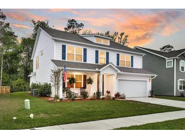 Beautiful two-story home with white siding, blue shutters, and an inviting front porch at sunset at 119 Loon Dr, Summerville, SC 29483