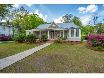 Charming home with a metal roof, inviting front porch with rocking chairs, and lush landscaping at 617 Hampton St, Walterboro, SC 29488