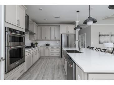 Modern kitchen featuring stainless steel appliances, gray cabinets, and a large island with a white countertop at 630 Coral Bells Ln, Summerville, SC 29486