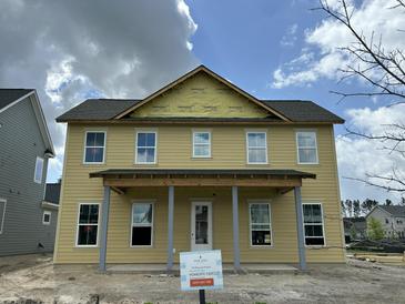 Two-story home featuring a welcoming porch and large windows, with construction in progress under a bright blue sky at 715 Blueway Ave, Summerville, SC 29486