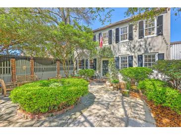 Charming two-story home with lush landscaping, stone patio, and classic black shutters offers inviting curb appeal at 73 Anson St, Charleston, SC 29401