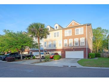 View of townhomes showing brick facades, white garage doors, palm tree and front yards at 9028 Parlor Dr, Ladson, SC 29456