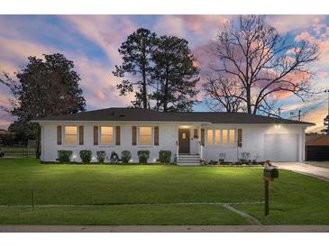 Charming painted-brick home with a well-manicured lawn and classic wood shutters at sunset at 1113 Smithfield Pl, Hanahan, SC 29410