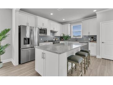 Bright kitchen features stainless steel appliances, island with seating, and white cabinets at 202 Garden Gate Way, Summerville, SC 29486