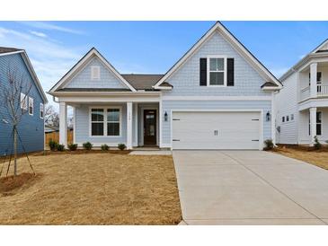 Charming light blue home with a two-car garage and manicured lawn on a sunny day at 347 Wappoo Trace Ln, Summerville, SC 29486