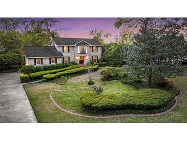 Charming two-story traditional home featuring a lush landscaped front yard with mature trees and manicured hedges at 506 Fairington Dr, Summerville, SC 29485