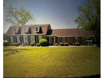 Charming brick home with a manicured lawn and a pop of color from the front door at 805 Horne St, Saint George, SC 29477