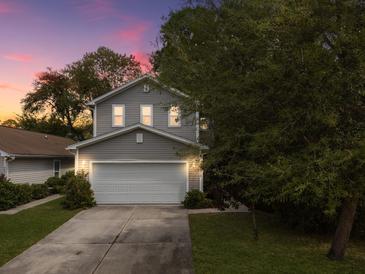 Charming two-story home features a gray exterior and a well-manicured front lawn at sunset at 8810 Gilston Ln, North Charleston, SC 29420