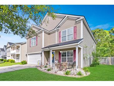 Charming two-story home featuring a landscaped front yard, cozy porch, and attached garage under a blue sky at 1252 Wild Goose Trl, Summerville, SC 29483
