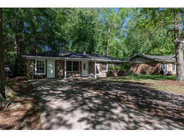 Charming single-story home featuring a brick facade, complemented by lush trees and a lengthy private driveway at 203 Elliott Dr, Ladson, SC 29456