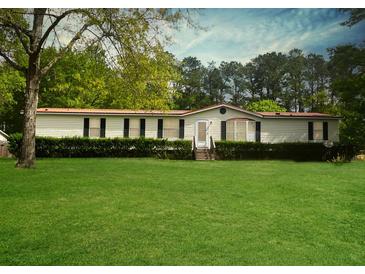 Well-maintained single-story home featuring a manicured lawn, mature trees, and a welcoming entrance at 570 Crystal Shores Dr, Moncks Corner, SC 29461