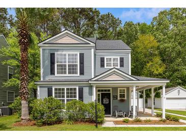 Charming two-story home with a covered front porch, manicured lawn, and a lush palm tree at 8986 N Red Maple Cir, Summerville, SC 29485