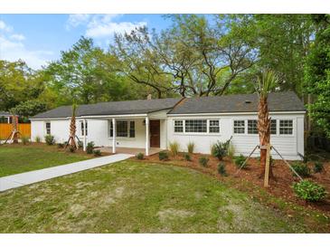 Charming single-story home with a well-manicured lawn and a cozy front porch and mature trees at 920 Julia St, Charleston, SC 29412