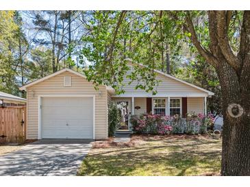 Charming single-story home with vinyl siding, an attached garage, and a well-maintained front yard with flowers at 1411 River Front Dr, Charleston, SC 29407