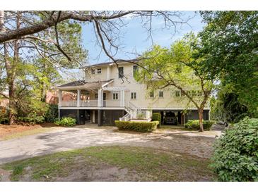 Charming two-story home with a spacious porch, lush landscaping, and ground level parking at 1651 Atlantic Ave, Sullivans Island, SC 29482