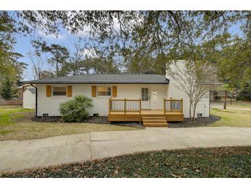 Charming home with a brick chimney and wood deck, complemented by lush landscaping and a welcoming entrance at 1897 Halo Ln, Charleston, SC 29407
