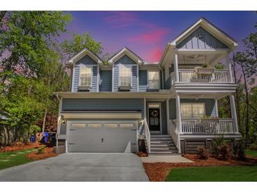 Charming home with a two-car garage, double porches, manicured lawn, and lush, mature landscaping at 2111 Nicholas David Path, Johns Island, SC 29455