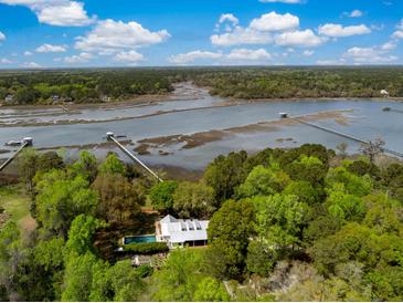 Aerial view of a beautiful house with a pool and surrounded by lush greenery and a waterfront at 3060 Bohicket Rd, Johns Island, SC 29455