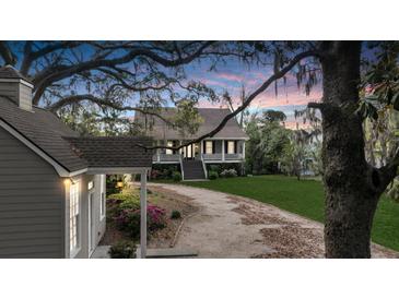 Charming two-story home featuring a picturesque wrap-around porch and a long, winding driveway through a lush, landscaped yard at 4584 Olde Smoak House Rd, Meggett, SC 29449