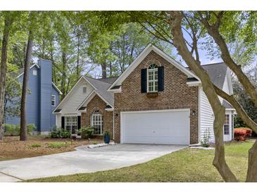 Charming two-story home with a brick facade, white garage door, and well-manicured landscaping in a lush, green setting at 1177 Old Ivy Way, Mount Pleasant, SC 29466