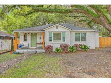 Charming white brick home with a quaint front porch and vibrant green door nestled beneath mature trees at 1188 Camden St, North Charleston, SC 29405