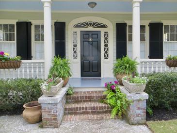 Charming home entrance with black door, decorative sidelights, brick steps, and lush potted plants at 141 Beaufain St, Charleston, SC 29401
