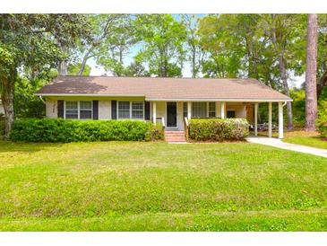 Charming single-story home with a well-maintained lawn, lush landscaping, and a covered carport at 1785 N Mayflower Dr, Charleston, SC 29412