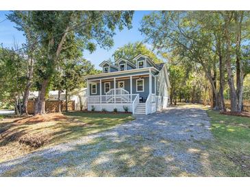 Charming two-story home featuring a welcoming front porch and gravel driveway surrounded by mature trees at 3683 Hilton Dr, Johns Island, SC 29455