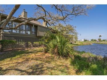 Beautiful home exterior with lagoon view and lush greenery on a sunny day with blue skies at 764 Summerwind Cir, Edisto Beach, SC 29438