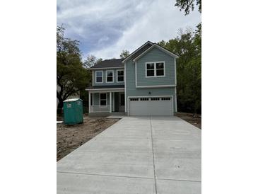 Charming two-story home with light blue siding, a front porch, and a large driveway leading to a two-car garage at 971 Beehive Rd, Awendaw, SC 29429