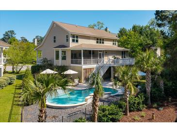 Stunning backyard featuring a pool, palm trees, deck, screened porch, and lush landscaping, creating an inviting outdoor retreat at 1339 River Otter Court, Mount Pleasant, SC 29466