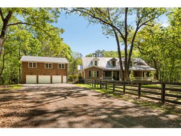 Charming brick home with three-car garage, complemented by a neatly fenced yard and mature trees at 5680 Dixie Plantation Rd, Hollywood, SC 29449