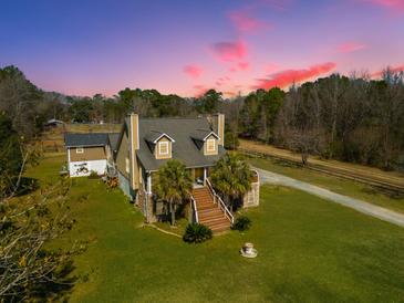 Charming exterior of a multi-story home with a lush green lawn and beautiful, clear colorful sky at sunset at 6440 St Anthony Dr, Hollywood, SC 29449