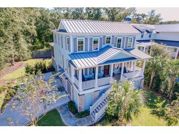 Stunning coastal home features a metal roof, shutters, and a welcoming front porch with stairs leading to a lush yard at 1212 Clonmel Pl, Mount Pleasant, SC 29464
