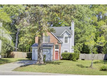 Charming two-story home with gray siding, red brick accents, mature trees, and a cozy, landscaped front yard at 1954 Treebark Dr, Charleston, SC 29414
