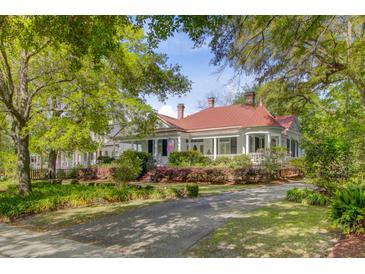 Charming home featuring a red roof, inviting front porch, and mature landscaping at 210 S Gum St, Summerville, SC 29483