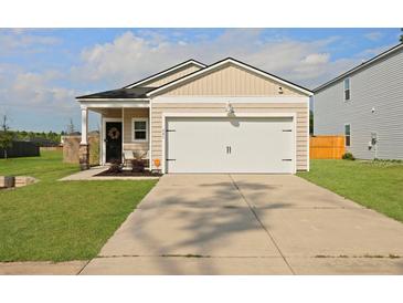 Charming single-story home featuring a front-facing garage, a welcoming porch and a manicured lawn at 341 Matuskovic Dr, Charleston, SC 29414