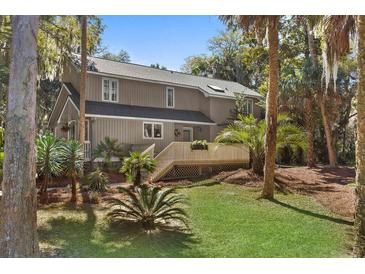 Charming two-story home featuring a well-maintained lawn, mature trees, and a spacious deck at 3510 Deer Run Rd, Seabrook Island, SC 29455