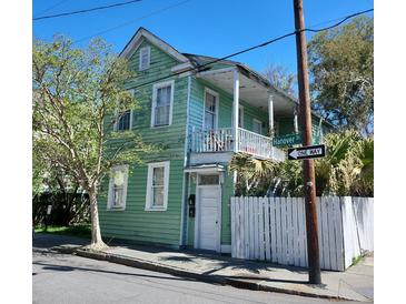 Charming two-story home with a balcony, white picket fence, and lush greenery at 2 Hanover St, Charleston, SC 29403