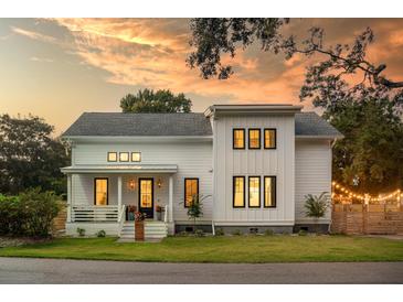 Inviting two-story home with white siding and a cozy front porch basking under a beautiful sunset at 2 Live Oak Ave, Charleston, SC 29407