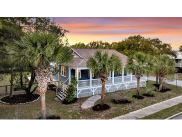 Charming home with a welcoming wrap-around porch and beautiful tropical landscaping at 2530 Jasper Blvd, Sullivans Island, SC 29482