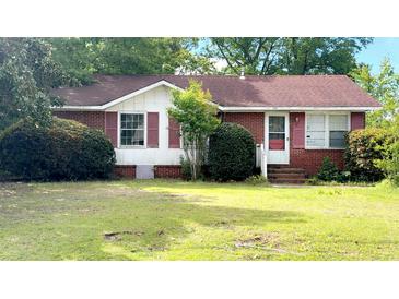 Cozy one-story brick home featuring red shutters, a classic design, and mature landscaping at 3293 Stonehaven Dr, North Charleston, SC 29420