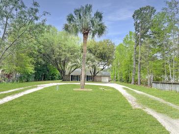 Charming home featuring lush green lawn, mature trees, and a long driveway for ample parking at 330 Crestwood Dr, Moncks Corner, SC 29461