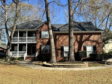 Charming two-story brick home featuring a double porch and mature trees accenting the front yard at 5496 Clearview Dr, North Charleston, SC 29420