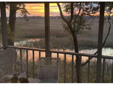 Charming porch view of a golden sunset over the tranquil marshlands and a picturesque tree at 642 Harbor Creek Pl # 21, Charleston, SC 29412