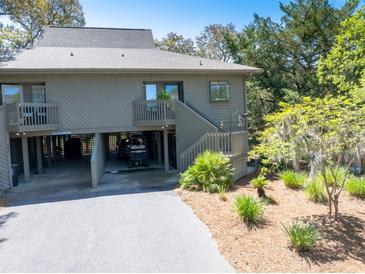 Exterior view of a two-story home with a driveway, landscaping, and a view of the surrounding trees at 754 Summerwind Cir, Edisto Island, SC 29438