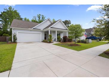 Charming single-story home features a well-manicured lawn, a two-car garage, and inviting front porch at 1513 Thin Pine Dr, Johns Island, SC 29455
