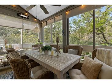 Inviting screened porch with a wooden table, wicker chairs, and tranquil views at 2401 Racquet Club Dr, Seabrook Island, SC 29455