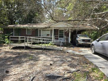 Modest single story house with ramp and small front porch, driveway, and mature landscaping at 719 Wantoot Blvd, Charleston, SC 29407